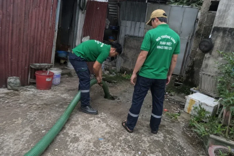 Hai nhân viên bố trí ống hút trên lối đi hẹp