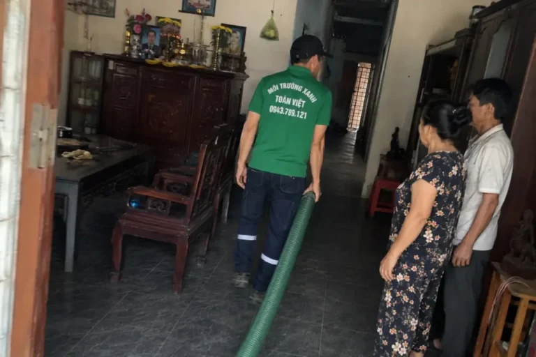 Hút hầm cầu Xuân Lộc giá rẻ uy tín | Toàn Việt 21 Nhân viên dẫn ống qua phòng có đồ nội thất