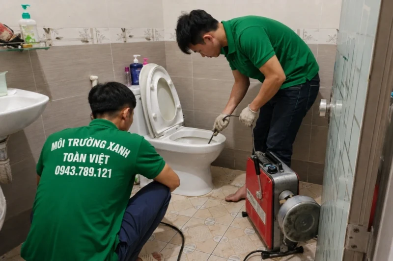 Hai nhân viên cùng dây máy lò xo bên bồn cầu – hướng dẫn thông bồn cầu Quận 3