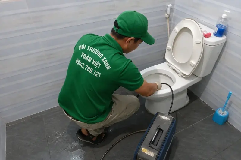 Nhân viên vận hành dây thông cạnh bồn cầu và máy màu xám