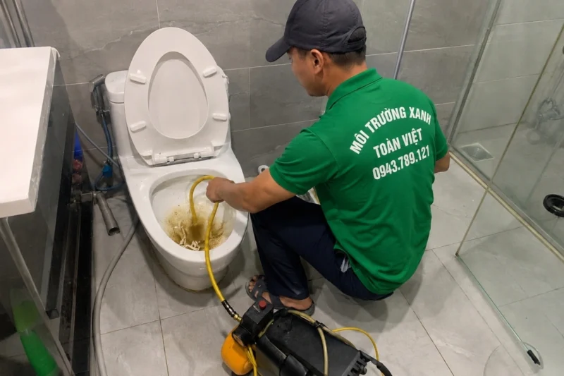 Nh&acirc;n vi&ecirc;n đưa ống m&agrave;u v&agrave;ng v&agrave;o l&ograve;ng bồn cầu