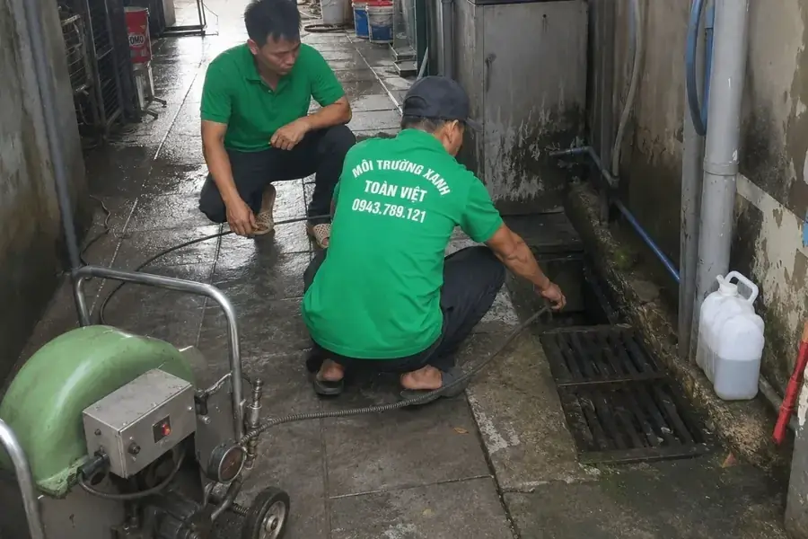 Hai thợ phối hợp bên rãnh thoát dưới bàn
